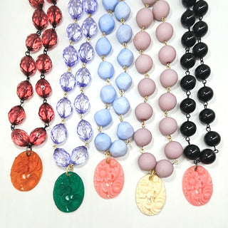 Set of colorful beaded necklaces with carved pendants on a white background