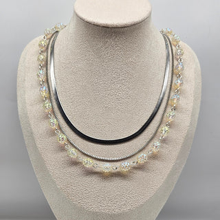 Silver necklace with multiple strands on a mannequin bust against a gray background