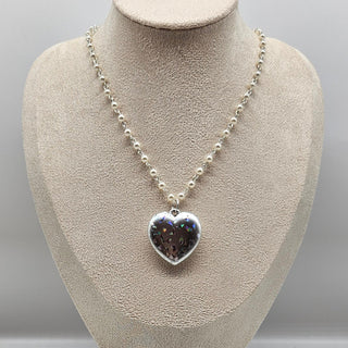 Necklace with a heart-shaped pendant on a mannequin bust against a gray background