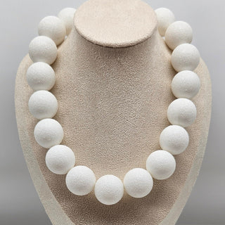 White spherical necklace on a beige mannequin bust against a gray background