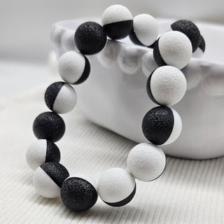 Black and white beaded necklace laid on a white bowl.