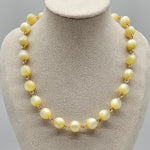 Cream colored moonglow beaded necklace on a mannequin bust with a gray background