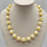 Cream colored moonglow beaded necklace on a mannequin bust with a gray background