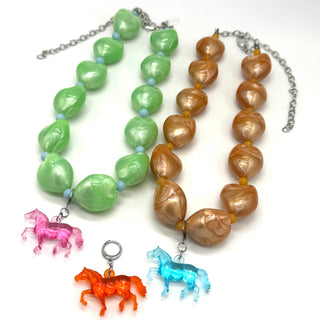 Two necklaces with green and brown beads and horse charms on a white background