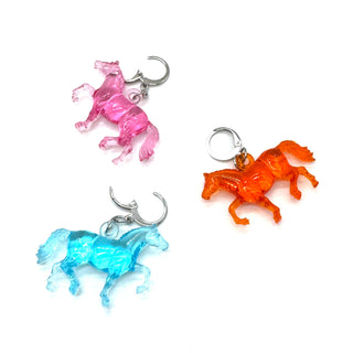 Three horse-shaped keychains in pink, orange, and blue on a white background