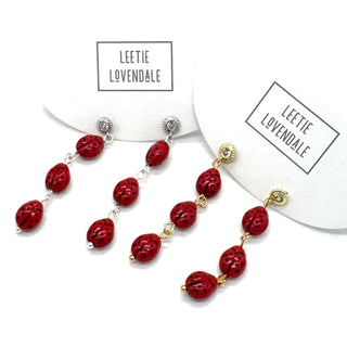 Red beaded earrings with gold accents on a white background, branded 'Leetie Lovendale'.