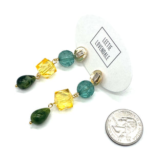 Multicolored beaded earrings on a white background with a coin for scale.