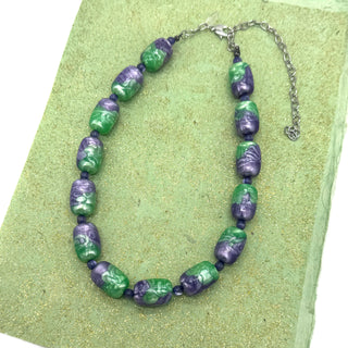 Necklace with green and purple beads on a green background