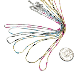 Set of colorful beaded necklaces with a coin for scale on a white background