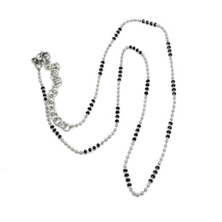 Silver necklace with black beads on a white background