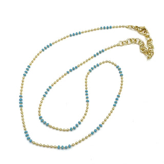 Gold and blue beaded necklace on a white background