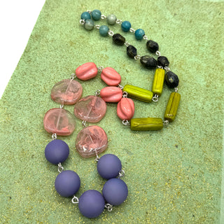 Colorful beaded necklace on a textured green surface