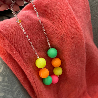 Necklace with colorful bead pendants on a pink fabric background