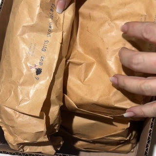 Brown paper packages being held by a hand with a visible brand logo.