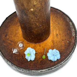 Flower-shaped earrings on a wooden stand