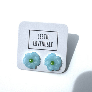 Light blue flower-shaped earrings on a white card with 'Leetie Lovendale' branding.