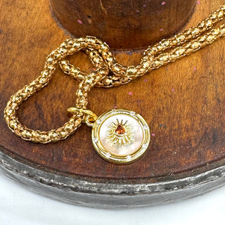 Gold necklace with a decorative pendant on a wooden surface