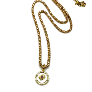 Gold necklace with a circular pendant on a white background