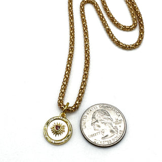 Gold necklace with a pendant and a coin on a white background