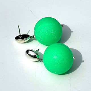 Green spherical earrings on a light gray background