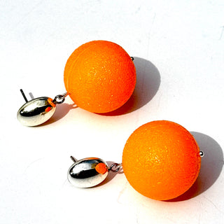 Orange spherical earrings with silver posts on a white background