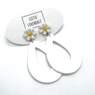 White hoop earrings with daisy flower charms on a white background