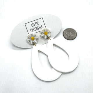 White hoop earrings with daisy flower charms on a white background with 'Leetie Lovendale' branding.