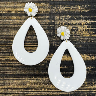 White teardrop earrings with daisy flowers on a textured black and gold background