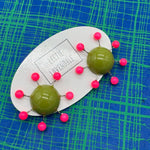 OlIve green earrings with hot pink beads radiating from center with posts on a blue and green plaid background.