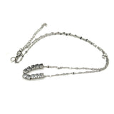 A silver necklace on a white background. It is a fine chain with several cube beads at the center.