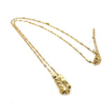 A gold necklace on a white background. It is a fine chain with several cube beads at the center.
