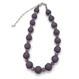 Adjustable necklace featuring dark gray and lilac lucite beads laid on a white background.