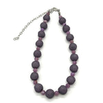 Adjustable necklace featuring dark gray and lilac lucite beads laid on a white background.