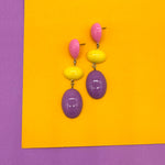 Colorful earrings on a yellow and purple background
