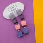 Colorful square earrings on a purple and yellow background with 'LEETIE LOVENDALE' branding.