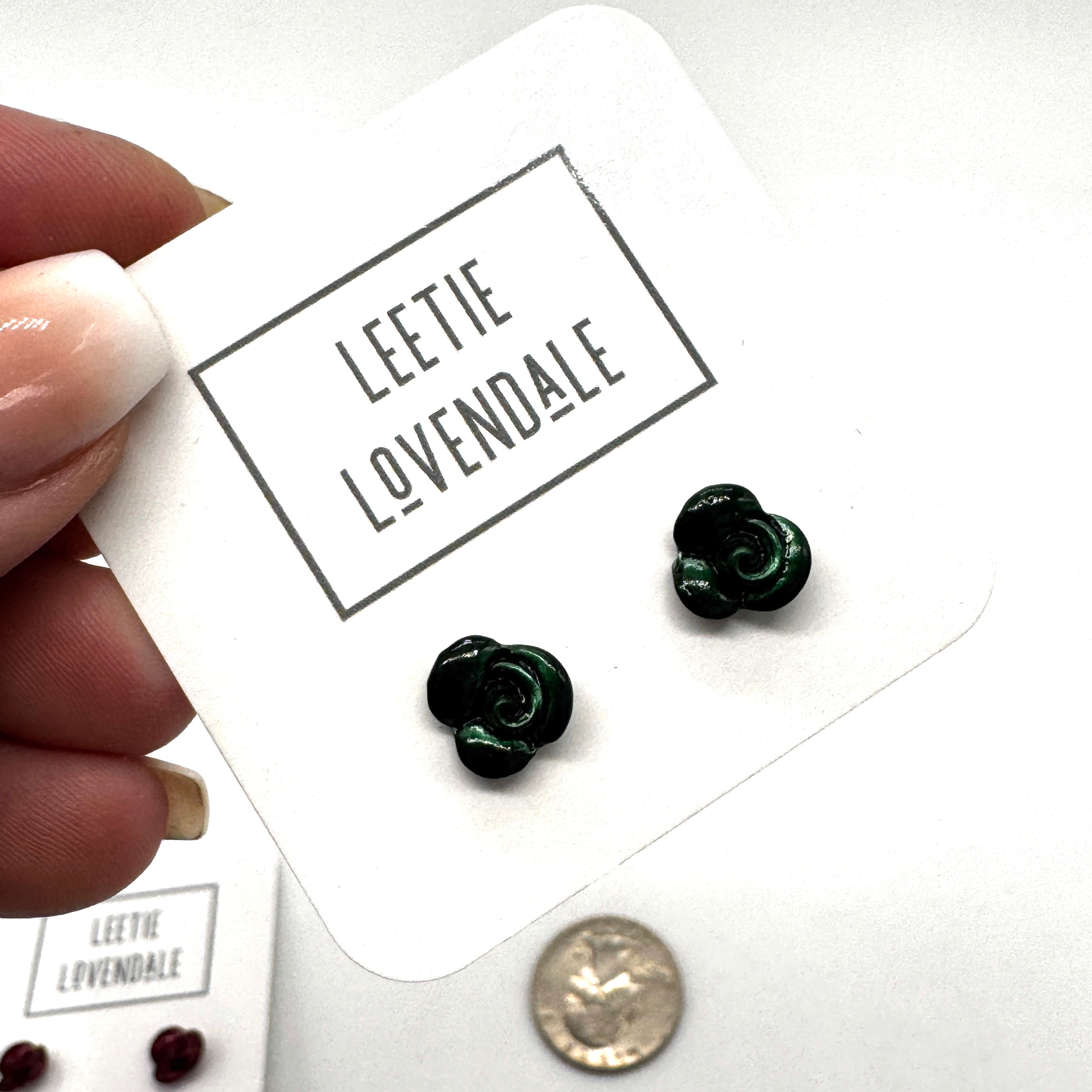 Green flower-shaped earrings on a card with 'Leetie Lovendale' branding, held by a hand.