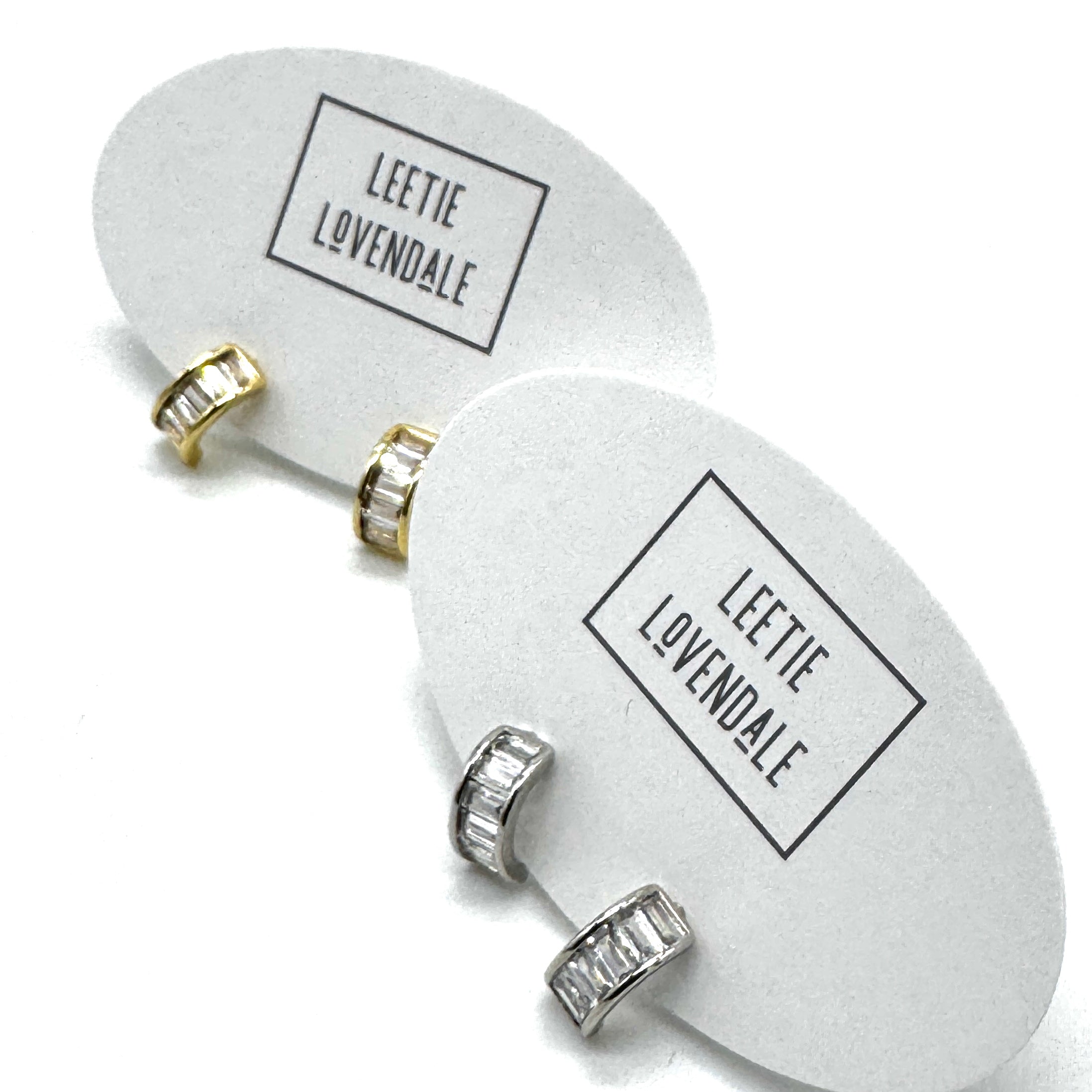Silver and gold crystal hoop earrings on branded earring cards.