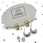 Silver and gold crystal hoop earrings on branded earring cards.