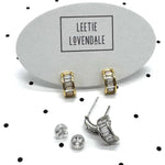 Silver and gold crystal hoop earrings on branded earring cards.