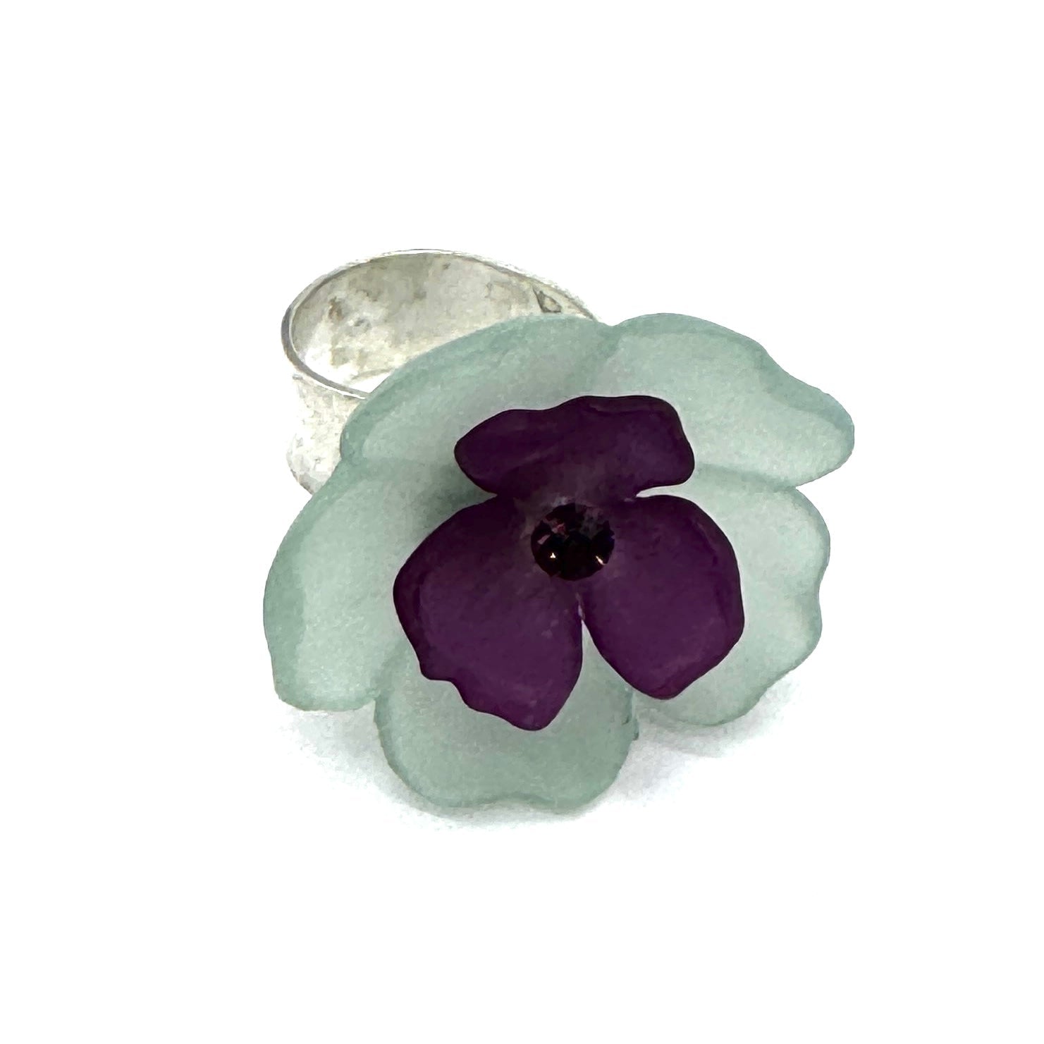 Teal and purple floral cocktail ring on a white background.