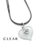 A silver snake chain necklace with a frosted clear heart-shaped pendant featuring a small silver heart in the center, shown on a white background with the word 'CLEAR' printed in the lower left.