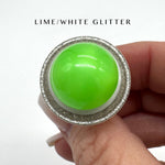 Green glittery ring held in a hand with 'LIME/WHITE GLITTER' text above.