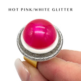 Hot pink and white glittery ring on a finger with text 'HOT PINK/WHITE GLITTER' above.