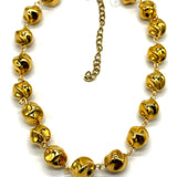 A gold-tone necklace featuring multiple small, shiny metallic beads linked by delicate chains, with an adjustable chain extender clasp, shown on a plain white background.