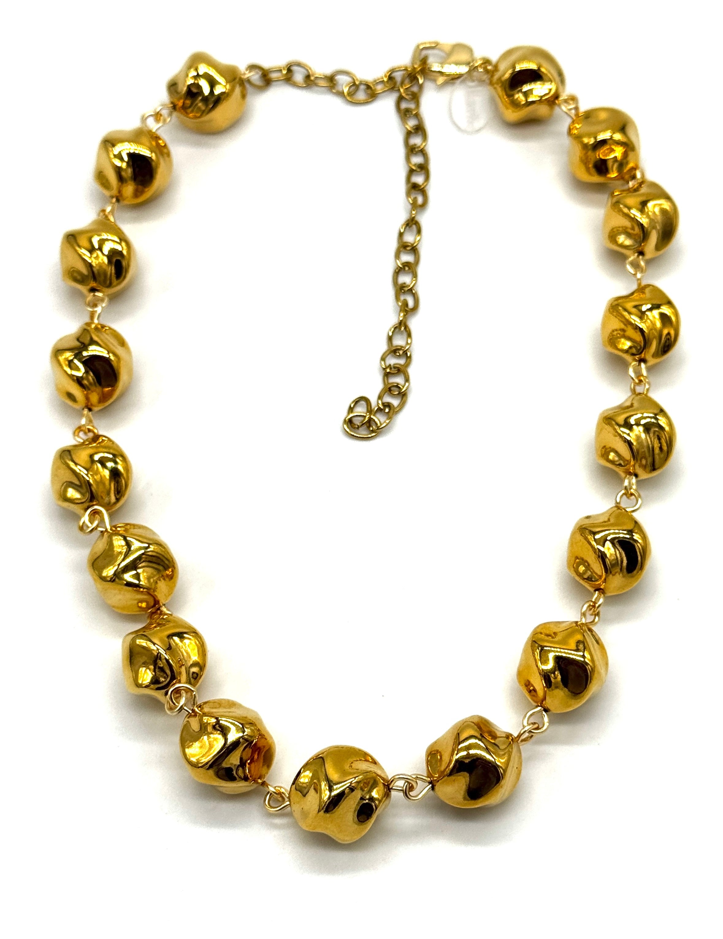A gold-tone necklace featuring multiple small, shiny metallic beads linked by delicate chains, with an adjustable chain extender clasp, shown on a plain white background.