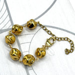 A gold-toned beaded bracelet with six irregular, polished beads connected by a delicate chain and extender clasp, displayed on a white background with faint gray circular line patterns.