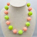 Peach and lime green beaded necklace on a cream colored bust.
