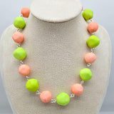 Peach and lime green beaded necklace on a cream colored bust.
