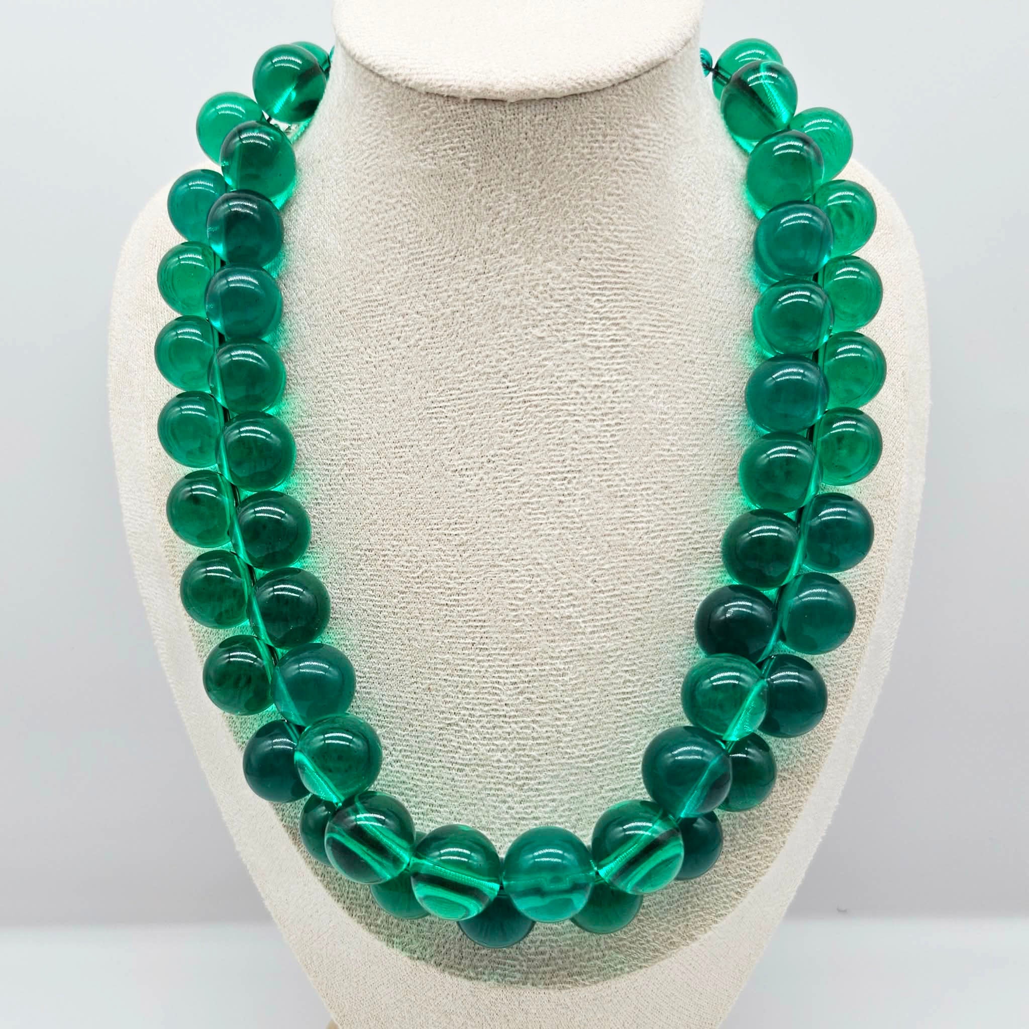 Transparent green beaded necklace on a bust.