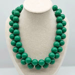 Opaque green beaded necklace on a bust.